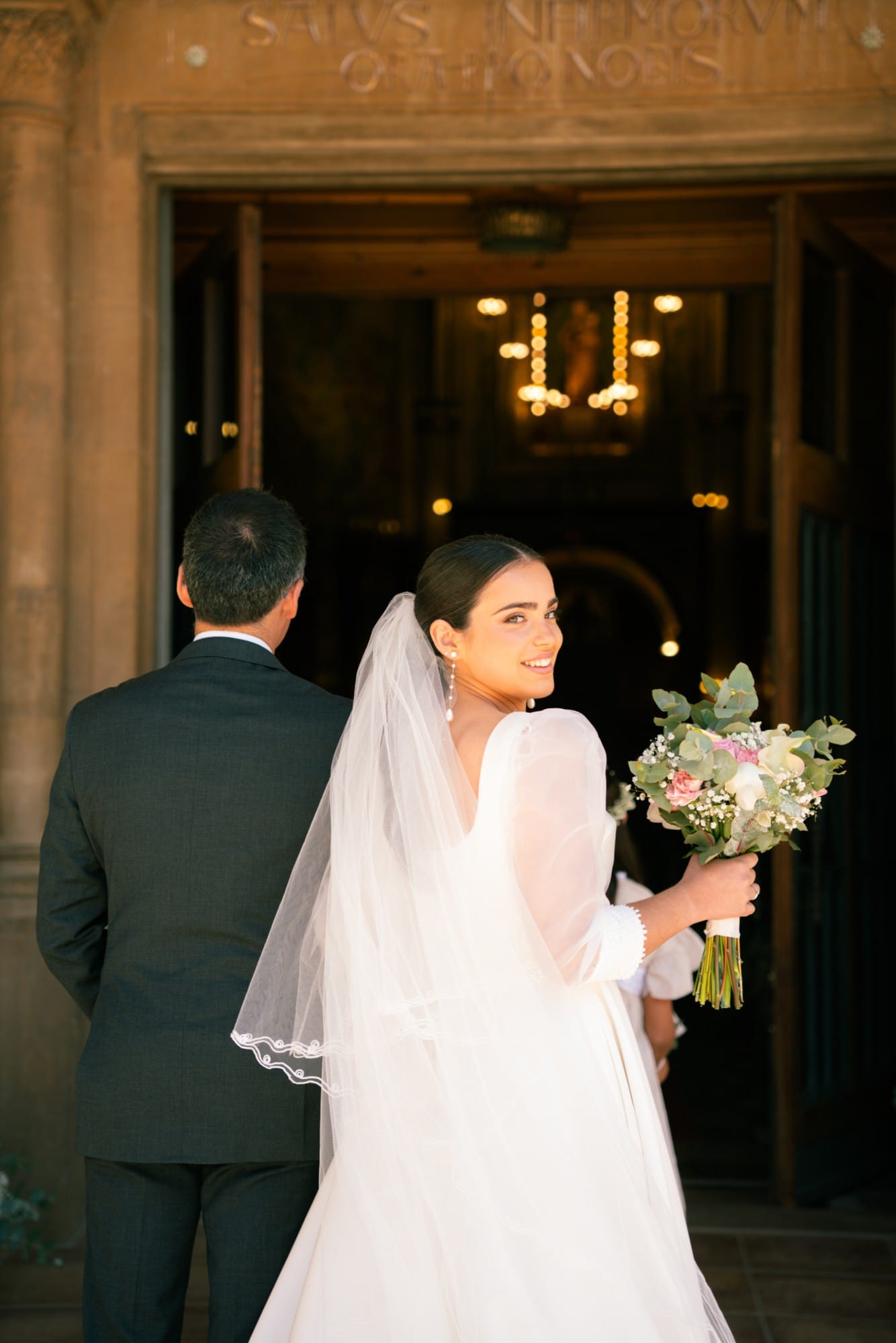 La novia mira atrás sonriendo a la entrada de la iglesia